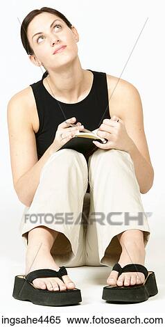 Stock Photography - Smiling young woman thinking and writing in book. Fotosearch