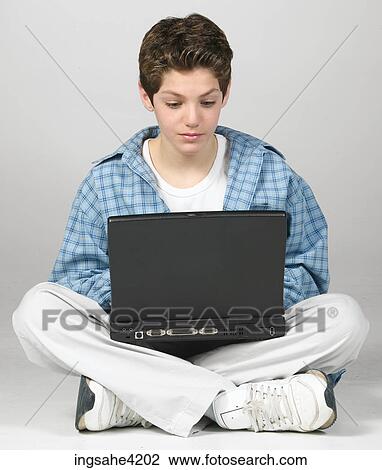 Stock Image - Teenaged boy using laptop computer. Fotosearch