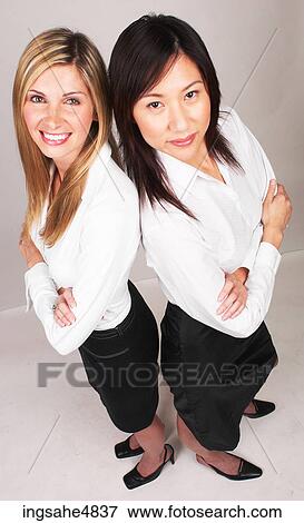 Two young business women standing back to back View Large Photo Image Stock Photo - Two young business women standing back to back . Fotosearch