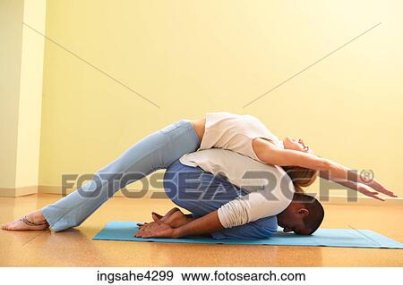 Stock Photo - Woman doing triangle pose with her yoga partner. Fotosearch
