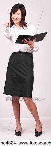 Young Asian business woman holding a notebook and pointing with her pen View Large Photo Image Picture - Young Asian business woman holding a notebook and pointing with her pen. Fotosearch