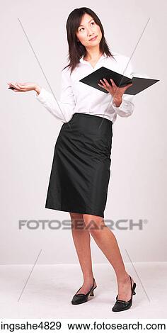 Young Asian business woman holding a notebook and gesturing with her pen View Large Photo Image Stock Photo - Young Asian business woman holding a notebook and gesturing with her pen . Fotosearch