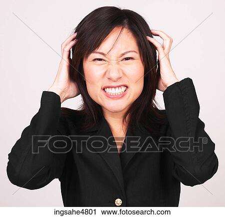 Young Asian woman holding her head and making an angry face View Large Photo Image Stock Image - Young Asian woman holding her head and making an angry face. Fotosearch