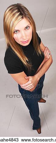 Stock Image - Young blond woman standing with her arms crossed in front of her. Fotosearch