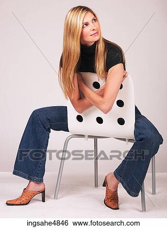Young blonde woman sitting backwards in a chair View Large Photo Image Stock Photograph - Young blonde woman sitting backwards in a chair. Fotosearch