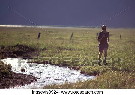 Picture - Man Jogging by Creek. Fotosearch