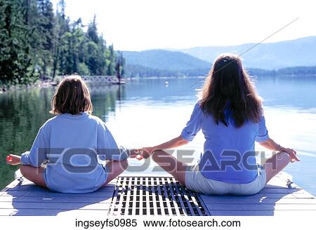 Stock Photography - Sisters Meditating by Calm Lake. Fotosearch