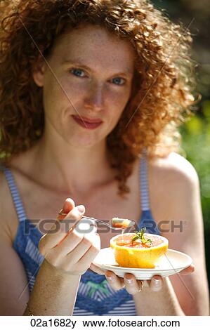 Stock Photo - A beautiful woman eating an orange. Fotosearch