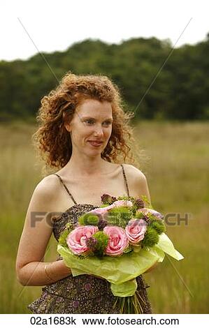 Stock Image - A beautiful woman holding flowers. Fotosearch