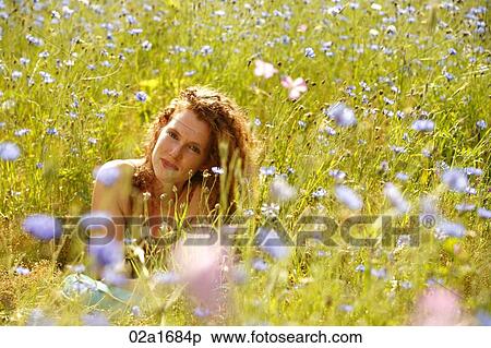 Stock Photography - A beautiful woman lying in a field of flowers. Fotosearch