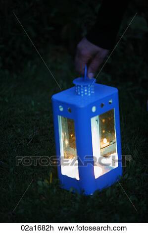 Stock Image - A hand holding a glowing lantern. Fotosearch
