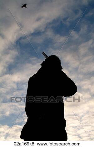 A man aiming his gun at a bird View Large Photo Image Stock Photo - A man aiming his gun at a bird. Fotosearch