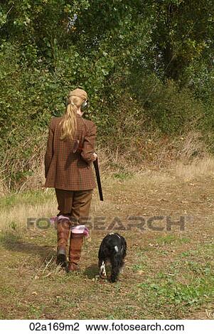 Stock Image - A woman with a gun and a dog. Fotosearch