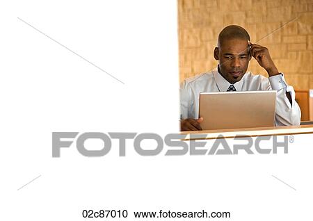 Stock Image - African-american businessman working on laptop.. Fotosearch