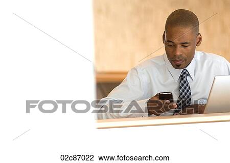 Stock Image - African-american businessman working on PDA.. Fotosearch