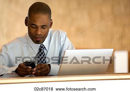 Stock Photo - African-american businessman working on PDA.. Fotosearch