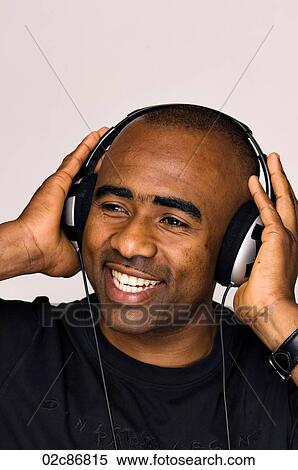 Stock Photography - African-American man listening to music on headphones.. Fotosearch