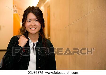 Stock Photography - Asian student holding knap-sack in school hallway.. Fotosearch