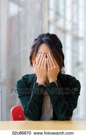 Stock Image - Asian woman covering eyes with her hands.. Fotosearch
