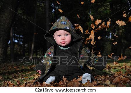 Stock Photo - Baby playing in the autumn leaves. Fotosearch