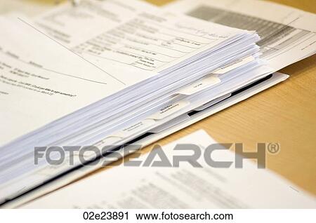 Stock Image - Binder with papers on office desk.. Fotosearch