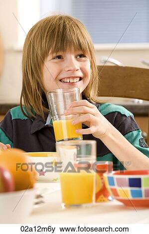 Stock Photo - Boy holding a glass of orange juice and smiling. Fotosearch