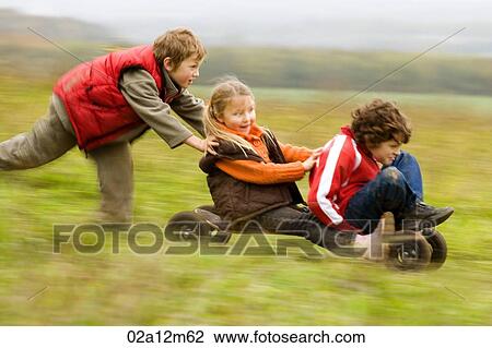 Boy pushing a mountain board with his friends sitting on it View Large Photo Image Stock Image - Boy pushing a mountain board with his friends sitting on it. Fotosearch