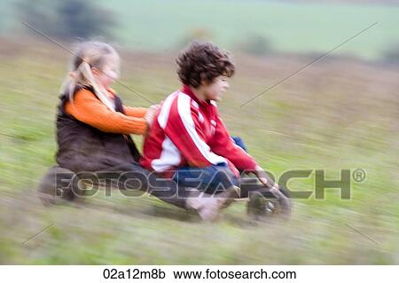 Boy with a girl riding a mountain board in a field View Large Photo Image Stock Image - Boy with a girl riding a mountain board in a field. Fotosearch