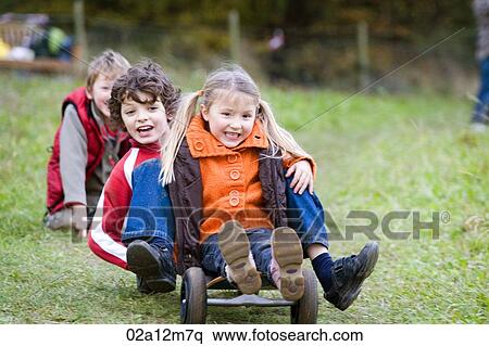 Stock Photography - Boy with a girl riding a mountain board in a park. Fotosearch