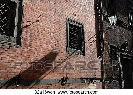 Stock Image - Brick exterior with street lantern at night in Siena, Tuscany, Italy. Fotosearch