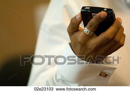 Stock Image - Business man using his PDA in the office.. Fotosearch