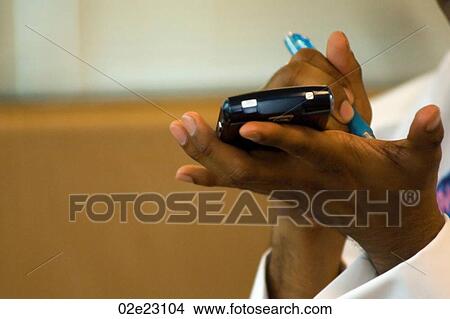 Business man writing notes on hand while holding PDA. View Large Photo Image Picture - Business man writing notes on hand while holding PDA.. Fotosearch