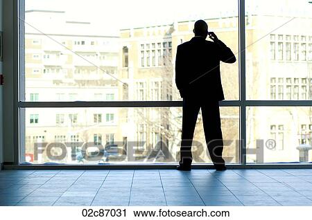 Businessman silhouetted in large office window. View Large Photo Image Stock Image - Businessman silhouetted in large office window.. Fotosearch