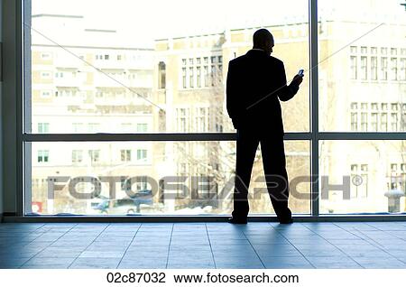 Businessman silhouetted in large office window. View Large Photo Image Stock Image - Businessman silhouetted in large office window.. Fotosearch