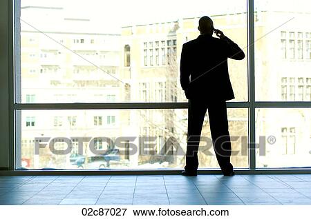 Businessman silhouetted in large office window. View Large Photo Image Stock Photo - Businessman silhouetted in large office window.. Fotosearch
