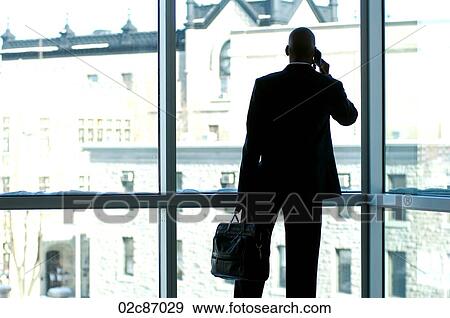 Businessman silhouetted in large office window. View Large Photo Image Stock Photo - Businessman silhouetted in large office window.. Fotosearch