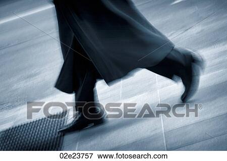 Stock Photo - Busy businessman walking on sidewalk.. Fotosearch