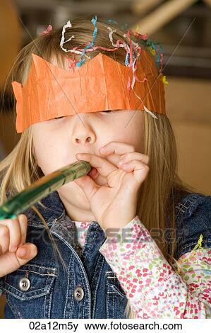 Stock Photo - Close-up of a girl blowing a party horn blower. Fotosearch