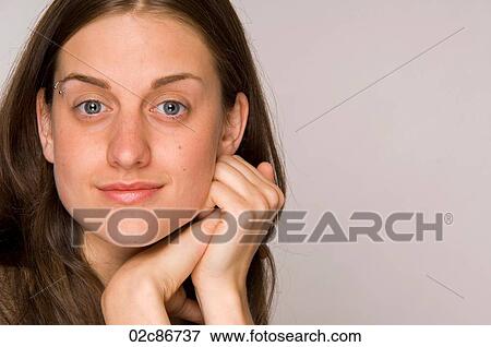 Stock Photo - Close-up portrait of beautiful young woman with hands to face.. Fotosearch