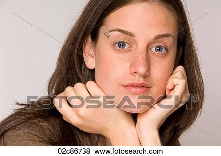 Stock Photo - Close-up portrait of beautiful young woman with hands to face.. Fotosearch