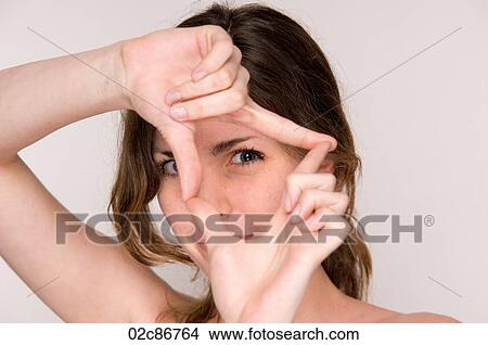 Picture - Close-up portrait of young woman, holding framing hands in-front of face.. Fotosearch