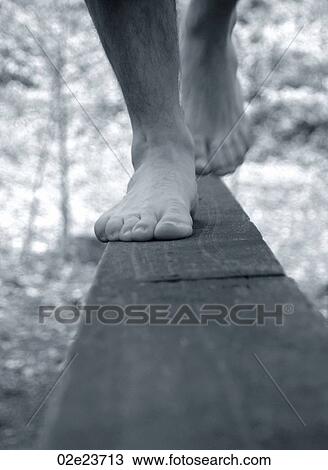 Stock Image - Feet walking on narrow wooden plank.. Fotosearch