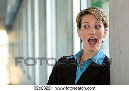 Stock Image - Female executive standing in hallway surprised.. Fotosearch