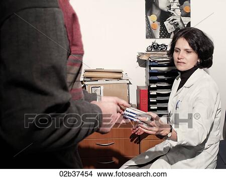 Picture - Female GP handing prescribed medication to patient. Fotosearch