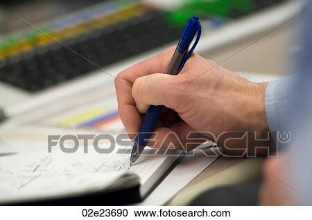 Stock Image - Financial analyst writing notes.. Fotosearch