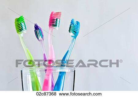Stock Photo - Four different colored toothbrushes in toothbrush holder.. Fotosearch