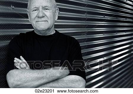 Stock Image - Friendly fit senior standing in front of corrugated steel.. Fotosearch
