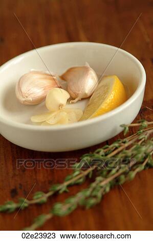 Stock Image - Garlic and lemon in a white bowl on table.. Fotosearch