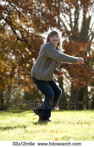 Stock Image - Girl playing on the grass and smiling. Fotosearch