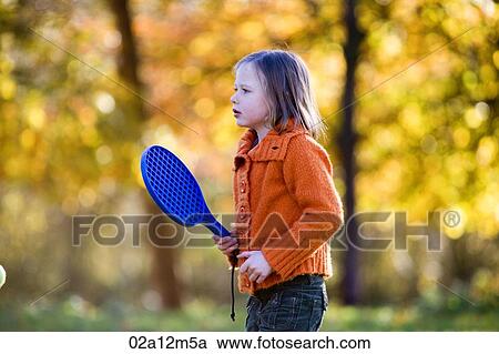 Stock Image - Girl playing paddle ball in park. Fotosearch